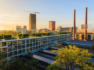 Former industrial buildings with glass roofs and two brick chimneys in Eindhoven at sunset